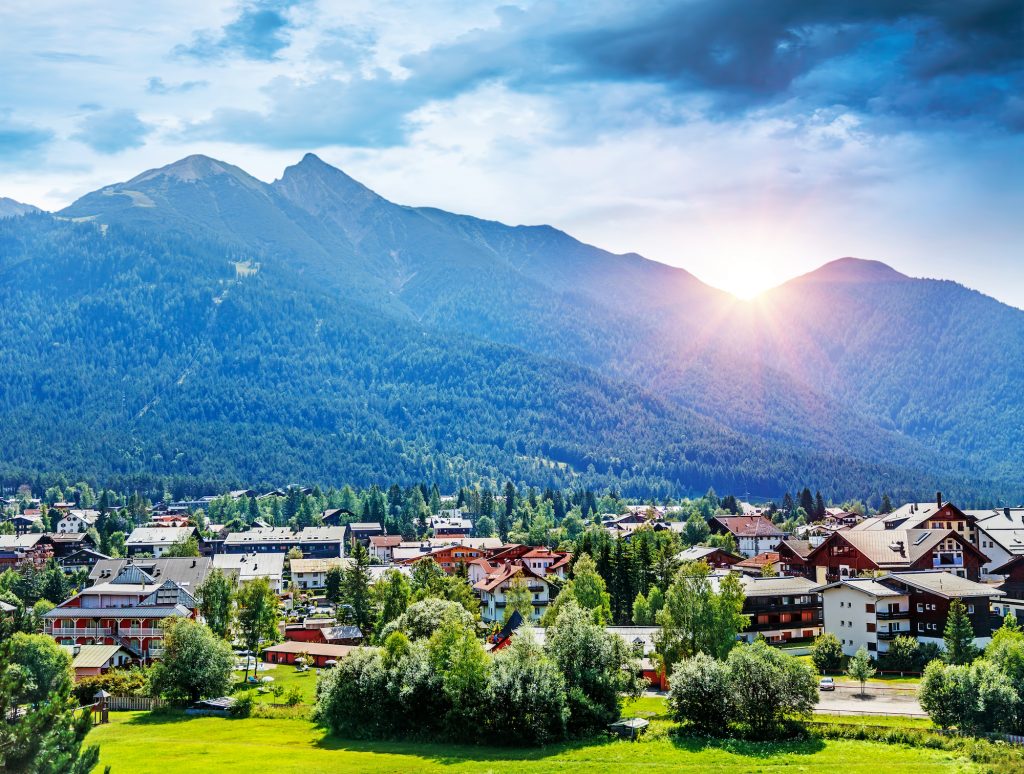 Blick auf eine Tiroler Gemeinde mit Ortskern und umgebenden Berghängen